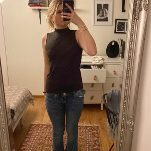 Svart ärmlös polotopp från YAYA - Säljer en stilren svart ärmlös polotopp från YAYA i storlek XS. Perfekt för lager-på-lager eller som den är. Toppen har en hög krage och är i ett mjukt material.