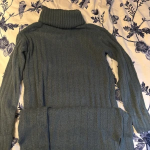 Grön/blå stickad klänning - Säljer en mysig grön/blå stickad klänning med långa ärmar. Perfekt för kyliga dagar och ger en stilren look. 