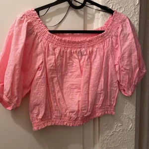 Rosa offshoulder blus från HM - Söt rosa offshoulder blus med broderade detaljer och puffiga ärmar. Perfekt för en somrig look med elastiska kanter för en bekväm passform.