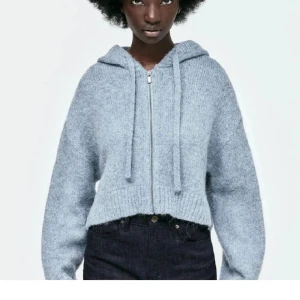 Blå stickad hoodie - Säljer en mysig blå stickad hoodie med dragkedja och huva. Tröjan är croppad och har långa ärmar, perfekt för kyliga dagar. Passar bra till jeans eller leggings för en avslappnad look. Använt skick