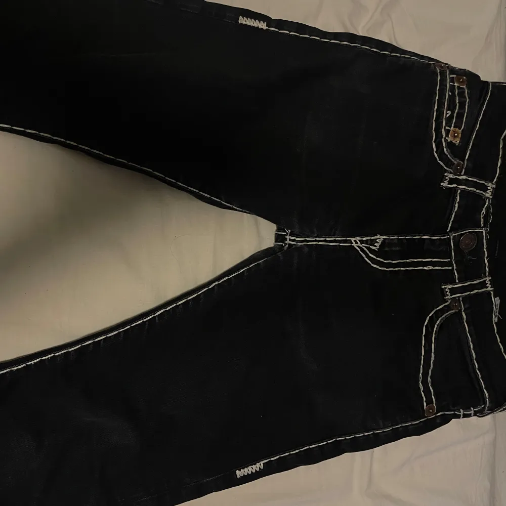 Snygga svarta jeans från True Religion med vita stitches, dom är i bra skick förutom att sömmarna är lite slitna på vissa ställen och ena fotändan saknar stitches. Pris kan diskuteras. Farkut & Housut.