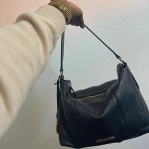 Michael Kors Brooke svart väska - Väskan har använts få gånger och kommer med dustbag och en längre remma. Bra kvalitet och är gjord av Kalvskinn. Nypris 2250kr