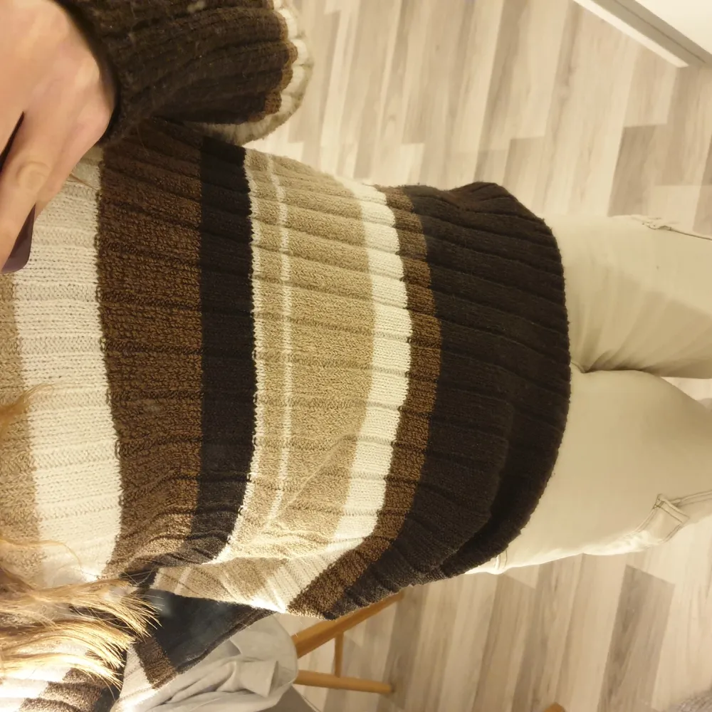 V-ringad stickad tröja. Den har olika nyanser av brun. Neuleet.