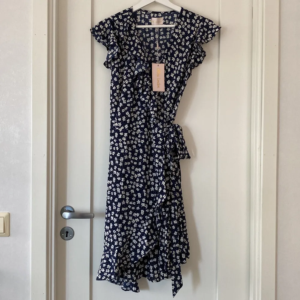 Säljer denna marinblå och blommiga omlottklänning. Inköpt på Smögen förra sommaren (2021) för 399kr. Aldrig använd och i fint skick! . Klänningar.