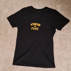 Vindar på mars t-shirt - Hov1 merch i form av en vindar på mars t-shirt, tryck på fram och baksida samt sydd logga på ärmen. Använd bl.a på deras konsert i Borgholm 2019 men i mycket gott skick!!  Säljer pga att den inte längre passar mig.