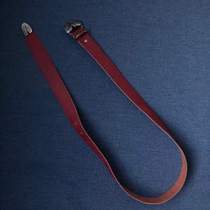 litet bälte i rött läder med buckle i metall i form av orm 