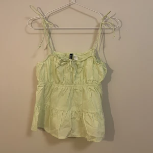Gullig topp - H&M. Ljus-limegrön minitopp med söta rosettknytning på axelband och framtill. Aldrig använd. 