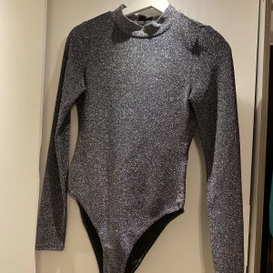 Body - Glittrig body från H&M med öppen rygg, storlek S använd en gång. Köpare står för frakt 