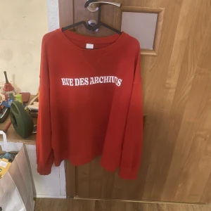 Röd sweatshirt med tryck  - En röd sweatshirt med tryck, en liten fläck där bak i nacken men annars jätte fin! 