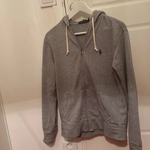 Polo Ralphlauren zip hoodie - En grå Polo Ralphlauren zip hoodie. Köpt var 1200. 10/10 i skick använd en gång. Frakt betalas av köparen