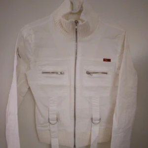 Vit vårjacka / sommarjacka. Strlk: Small / 36.  Bra skick. - Vit vårjacka / sommarjacka.   Strlk: Small / 36.  Material: Bomull.  Stängs med dragkedja och har fickor samt hög, stretchig krage.  Bra skick. 