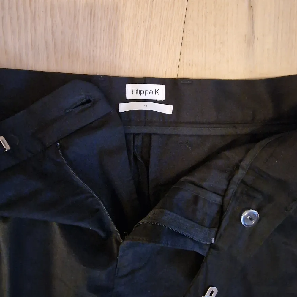 Ett par svarta och lätt blanka byxor från Filippa K med diskreta pressveck.  Storlek 44. Slim passform  Knappt använda.. Jeans & Byxor.