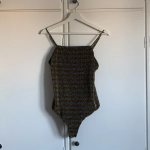 Glittrig body  - Guld och silverglittrig body från BikBok i storlek M. Mycket gott skick, endast använd 1 gång.