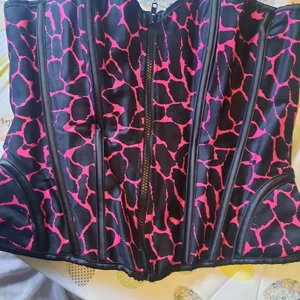 Läcker korsett rosa/svart♡ - Skitläcker,går upp över tuttarna. Väldigt långa snören så den går att ställa ut rätt långt. Använd 2 ggr. Okänd storlek men jag hade den både som L och M. Smidig med dragkedja.  Djur och rökfritt hem, samfraktar!