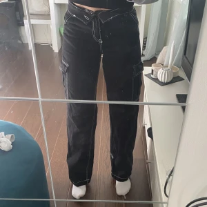 Cargo byxor  - Svarta cargo brallor med vita sömmar. Jättefint skick då de är använda max 3 ggr från H&M