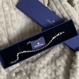 Swarowski armband  - Ett tennisarmband från Swarowski med Swarowski kristaller. Behållaren medföljer men är lite defekt. Aldrig använd. 