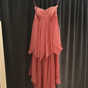 Klänning - En super snygg smutsrosa klänning utan armar med snörning bak och paljetter och diamanter fram. Den passar mellan xxs till s. Den är kort fram med ett ”släp” baktill. Finns i Nässjö 💕