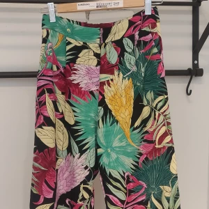 Blommiga byxor från Monki. - Hög midja, kortare vida ben.  100% polyester  Sparsamt använda och i gott skick. Säljes då de är lite för små för att sitta riktigt snyggt 