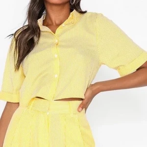 Kortärmad skjorta i kort modell - Skjortan är randig i vit och gul, ingen av bilderna gör färgen rättvisa. Det är en väldigt fin neutral gul. Skjortan är kortärmad och lite kroppad i modellen. Från IvyRevel. Strl 36. Frakt ingår ej i priset🍓