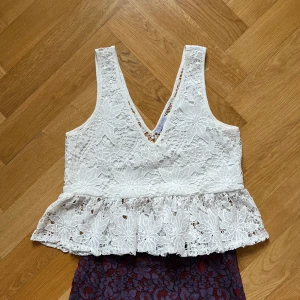 Spets top - Spetstop, lite kortare, crop top med spetsvolang som täcker en del av nedre delen av magen. Lätt att ha på och snygg v-skärning.. från Zara, nytvättad. Hel. 