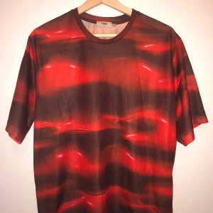 CMMN SWDN Lava Lamp tee - CMMN SWDN Tröja. Spontanköp från Tres Bien för flera år sedan. Aldrig använt den då den inte riktigt varit min stil. Nyskick förutom tagen som blivit lite missfärgad på något sätt. Hängt i garderoben ca 7-8 år.   Boxig och lite oversized passform. 