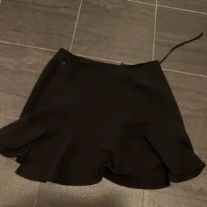 Svart omlottkjol - Svart omlottkjol från hm. Säljer då den blivit för stor för mig. Använd ett tiotal gånger, bra skick. Köparen står för frakt. 