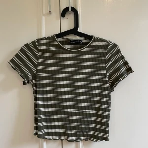 Randig topp - En oanvänd militär-grön-randig topp i storlek 38. Dock liten i storleken. Säljer pga ingen användning. Aldrig använd. Köpt på ASOS