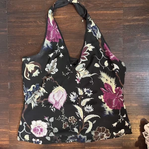Halterneck topp - Skitsnygg halterneck topp som är svart med blommor och mönster på!