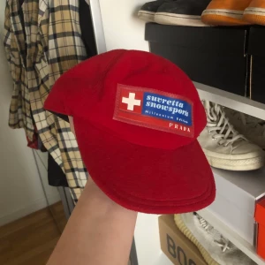 Vintage Prada keps - Säljer denna feta Prada keps! Inte sett någon liknande, en riktigt unik keps. Den är i bra skick utan några skador.  Skriv om du har några frågor och skriv innan köp!