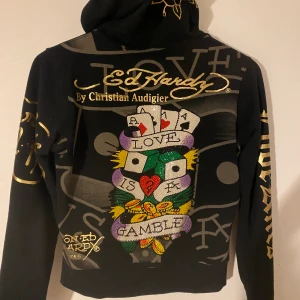 Ed hardy zip up - En ed hardy hoodie i storlek m, dock är den liten i storleken så skulle passa xs-s skulle jag uppskatta. Alla rhinestones är kvar på ryggen. Dragkedjan kan vara svår och få upp ibland men funkar ändå. Köpt för 600kr här på Plick.