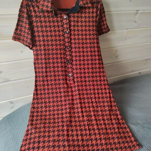 Hundtandsmönstrad klänning - Orange och svart hundtandsmönstrad klänning i strl 12. Tror det motsvarar small/medium. Material 96% viskos och 4% elastan. Kommer från djur och rökfritt hem. Frakt betalas av köpare. Om man vill ha annat fraktalternativ så går det att ordna. Betalning sker via Swish och varan skickas så fort betalningen inkommit. Jag ansvarar inte för postens slarv. Bud är bindande. Samfraktar gärna.
