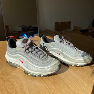 Nike 97 Silverbullets  - Klassiska Nike air max 97 i unika kulören silverbullets. Använda men överlag fint skick främst vissa delar av sulan som blivit lite missfärgade. Märkta som en storlek EU40/UK6/US7/25cm sula. Kan mötas upp i stockholm på södra sidan av stan, annars fraktar jag på köparens bekostnad för 66kr vilket är spårbar frakt! Skriv vid frågor💌