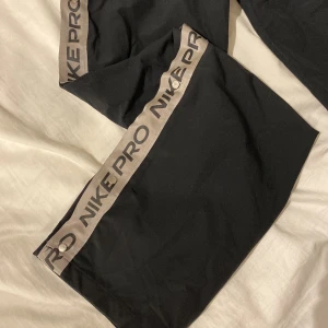 Nike byxor - Fina byxor med knappar längs benen. Lite täcken på användning men har haft dem länge och de är ffr superfina. Sitter åt vid midjan och är raka i modellen. Sydda vid höfterna för att inte knapparna ska öppnas men det går lätt att sprätta. Nypris ca 500