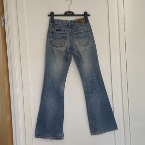 Jeans Low waist - Uppskattad low-waist jeans i ljusblå färg och detaljer på fickorna. En av bälteshållarna har åkt bort bak, se bild 3. Mått: Waist - ca 34cm rakt över och hyfsat stretchigt material, innerben - 75cm ( går ej att få fitpic då plagget är för litet) BRA skick