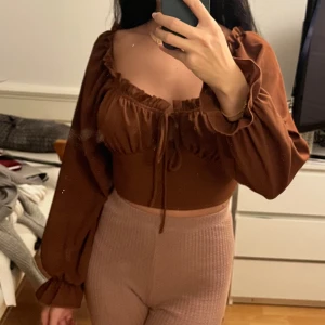 Brun top - Jättefin brun top med ballongärmar, fina detaljer. Går att justera själv med snöret vid brösten.