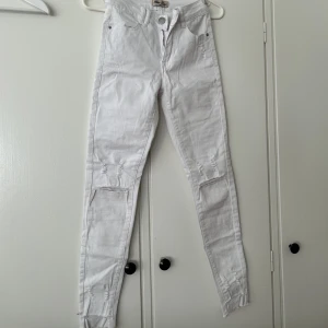 Vita jeans. - Vita lågmidjade jeans med hål på båda knäna.