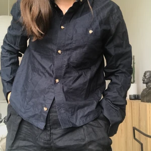 Skjorta från Weekday - Långärmad skjorta från Weekday. Ficka på vänster bröst. Skjortan är omsydd kortare i längden. / STORLEK: Herr S / MATERIAL: Lappen är borta från kortningen, men känns som 100% bomull! / SKICK: Fint skick, som sagt omsydd men annars som ny!