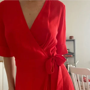 Röd omlottklänning från &Other Stories - Jättefin och smickrande klarröd klänning med knyt från & Other Stories säljes då den inte kommer till användning. Vadlång. Omlott med knyt. Använd men i mycket gott skick! 