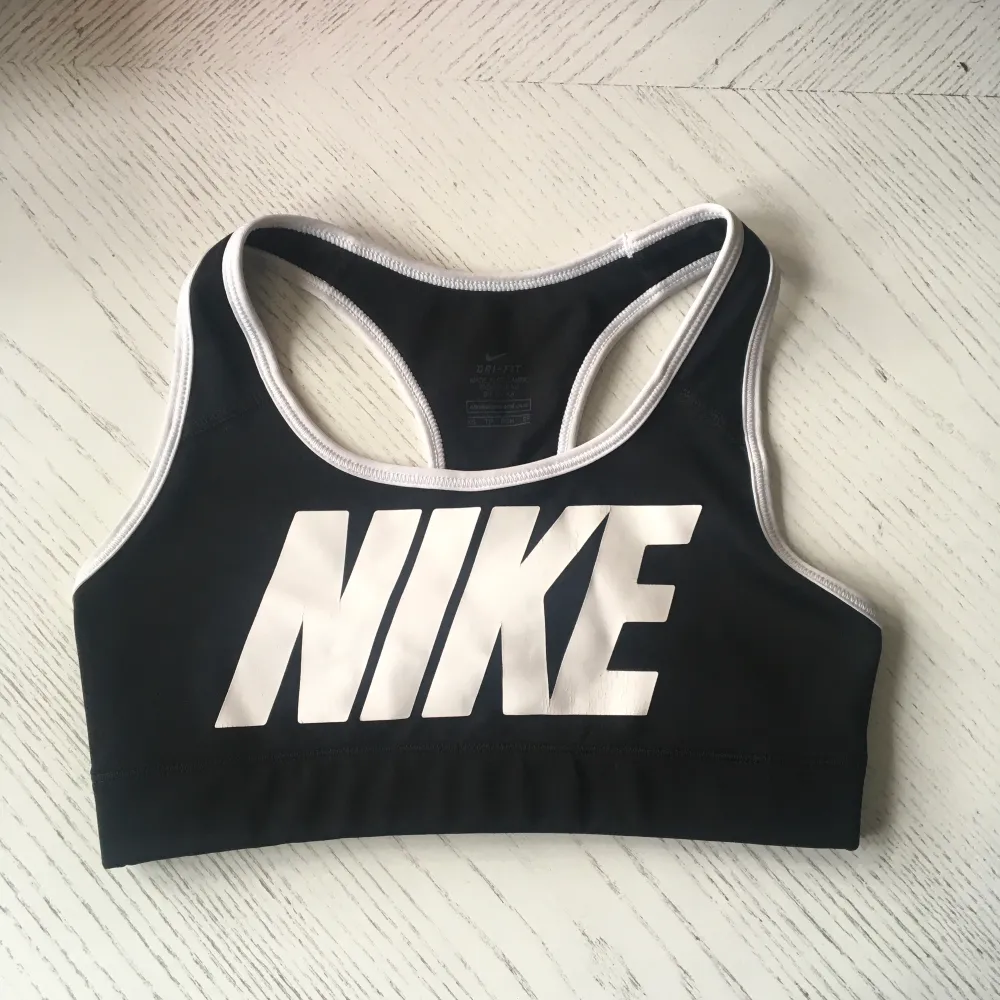 Nike Dri Fit träningstopp i svart/vitt. Storlek Xs. Syntetmaterial. Okej skick - slitage i form av sprickor på Nike-trycket efter tvätt, annars sparsamt använd. Köpare betalar frakt.. Toppar.