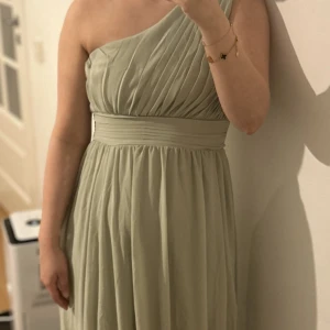 Ljusgrön one shoulder klänning - Helt ny lång klänning i storlek 38. Jag köpte den för min bal men ska inte längre gå därav säljer jag den.