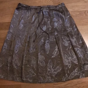 Kjol strl S - Jättefin brun kjol med fjärilsmönster. Den är i storlek 38 men den passar även mig som har storlek 34/36 då den har ett snöre. I fint skick 