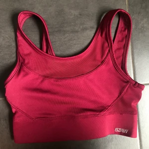Träningstopp - Träningslinne/sport-bh i vinrött. Stängs med dubbla hyskor och hakar i ryggen. Dubbel mesch ovanför brösten och på ryggen. 