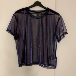 Multichrome färgad topp - En glansig Multichrome skiftande topp/t-shirt med svart bas och genomskinligt tyg. Använd några gånger men i fint skick. Ännu mer skiftande i verkligheten, från lila till rosa/röd till turkos och blå