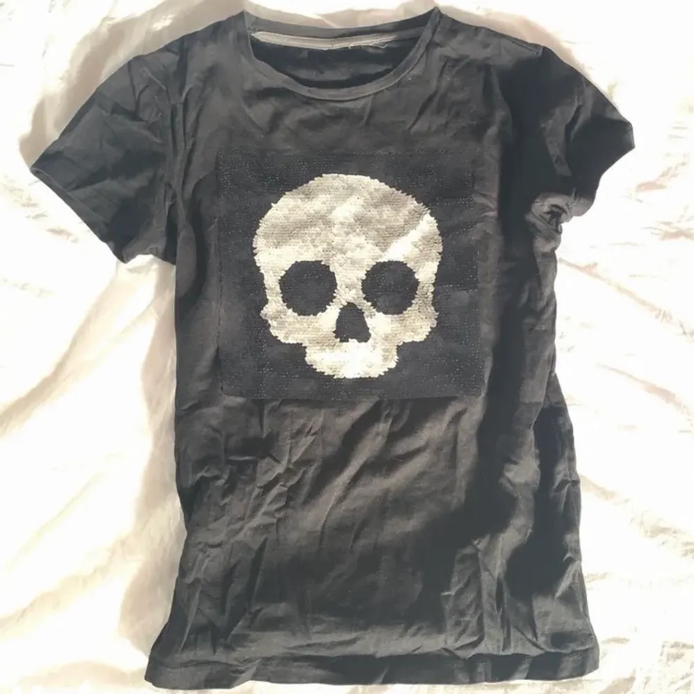 Cool svart t-shirt i lite kortare o tajtare modell med en dödskalle i paljetter på ☠️ paljetterna går att flippa så att de byter färg🎉. T-shirts.