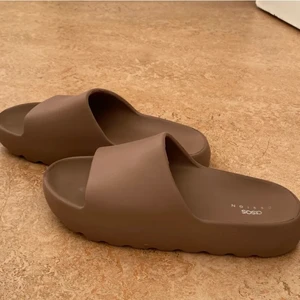 Bruna tofflor - Tofflor från ASOS i storlek 40. Men passar 38-40. Färgen är en mörkare brun i verkligheten. Använd fåtal gånger så dem är som nya! 