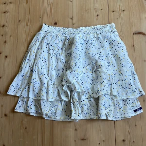 Vit kjol med blåa och gula prickar - Denna vita kjol med gula och blåa prickar säljer jag för 50 kr + frankt. Den är i god kvalite och är köpt i Frankrike. Den är från Lili Gaufrette och är för 10 åringar.