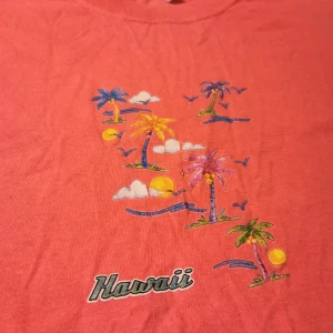 Croppad Hawaii tisha - Unik färg, typ en orangeig mörk persika, första bilden är närmst. Jätte gulligt print i mitten. Köpt secondhand. Om du vill ha bilder eller undrar något så är det bara att fråga! :) 