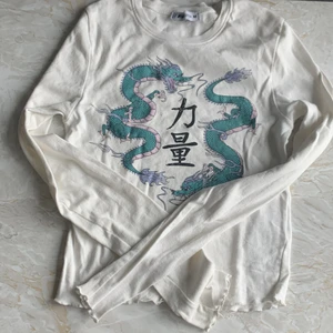 Långärmad tröja från New yourker - En vit långärmad tröja med en grön blå drake på! Från new yourker