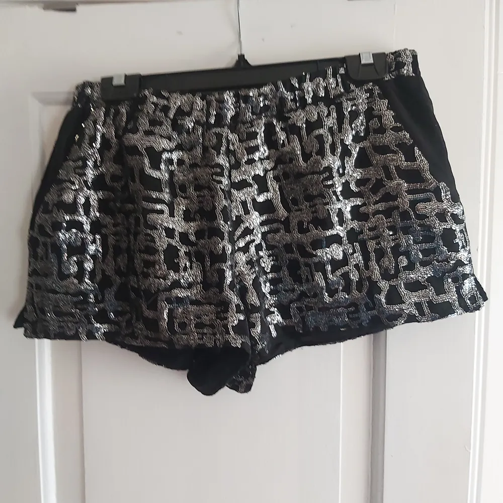 Svarta minishorts med silverglittrigt mönster med fickor från Urban Outfitters (strl M). Shorts.