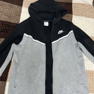 Nike tech fleece Junior - Säljer min gamla Nike tech fleece som jag köpte från JD sports. Den är i bra läge, storlek (XL=158-170cm) i junior size. Färg svart/grå